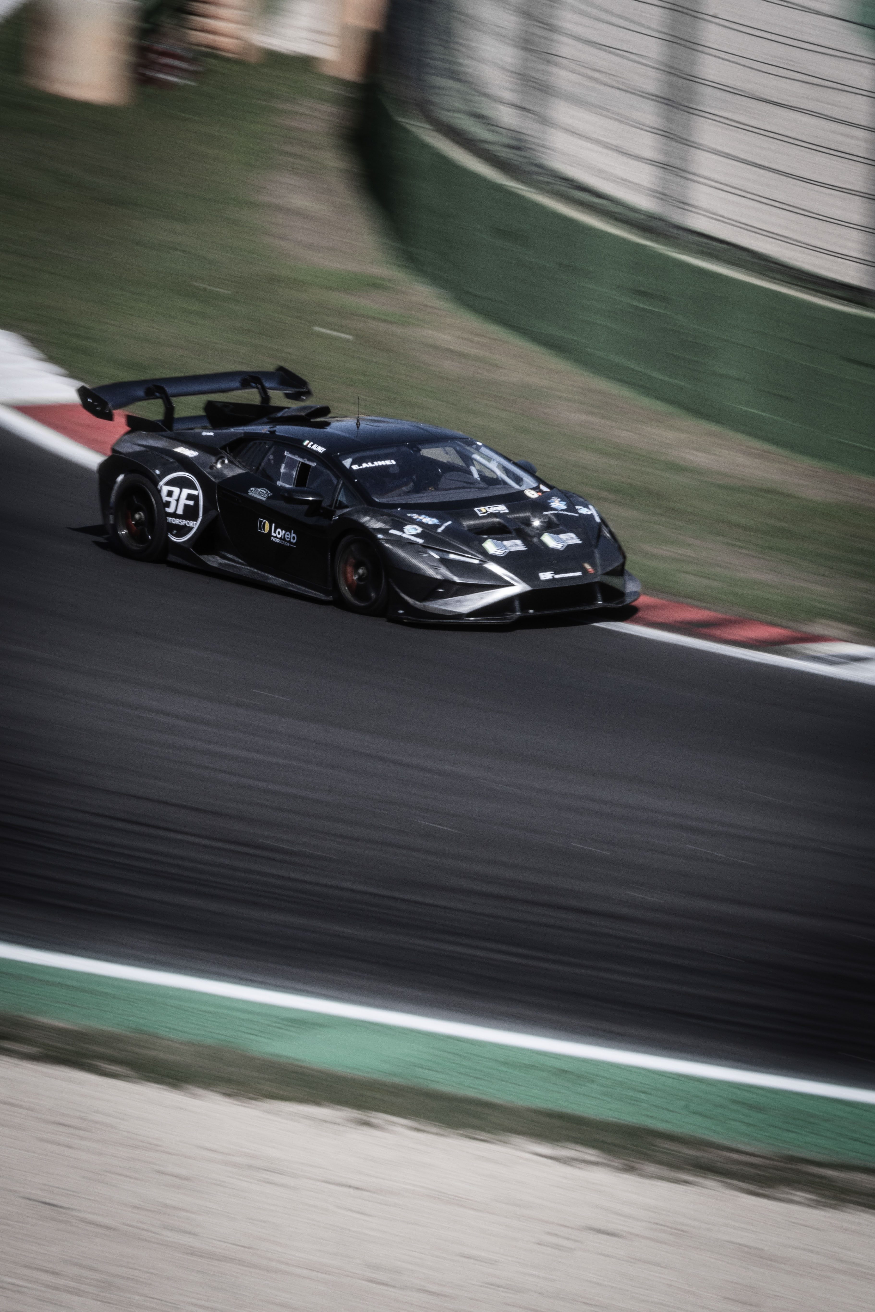 Auto GT nera in curva sul circuito, effetto mosso