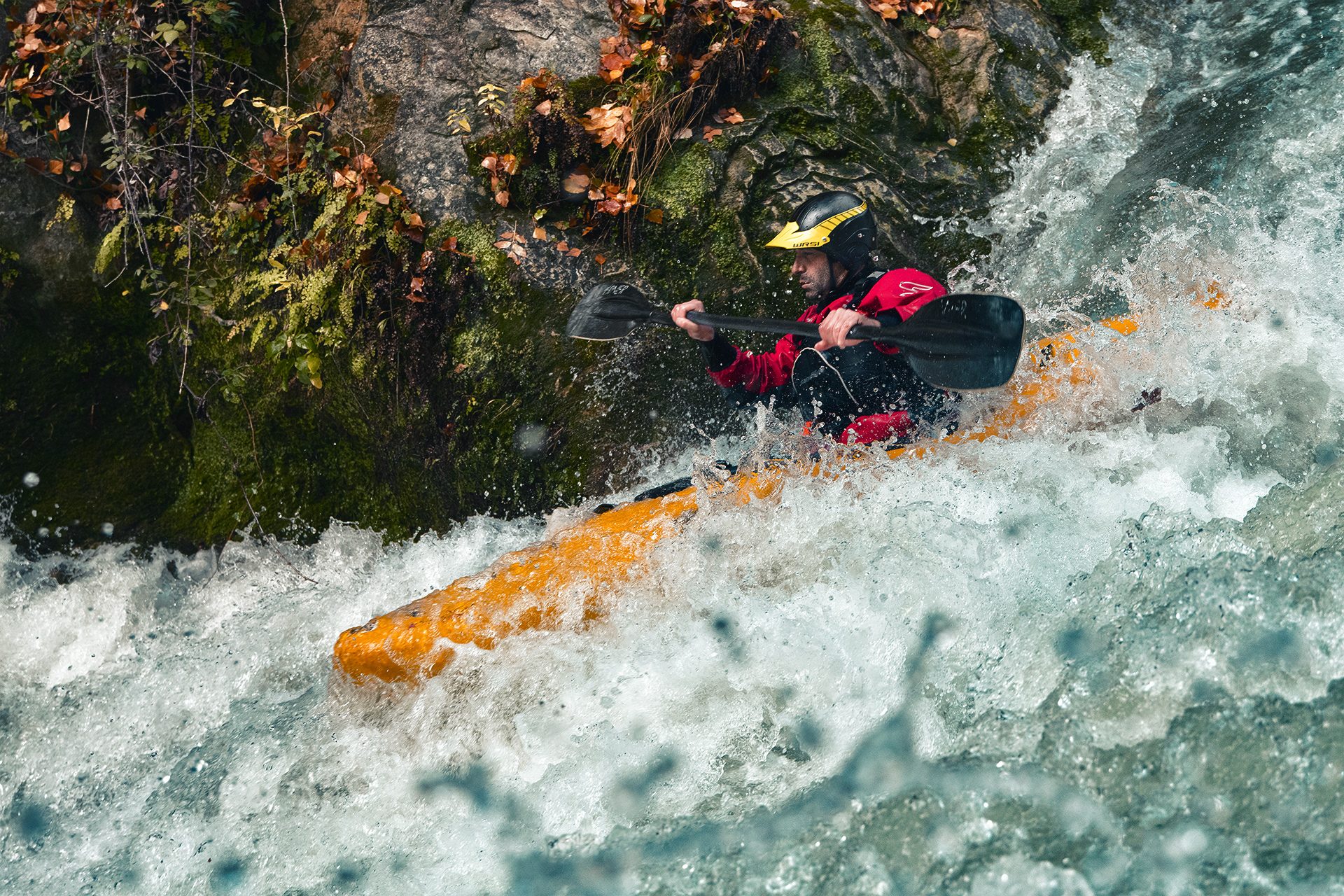 Kayaker in una rapida tra rocce coperte di muschio