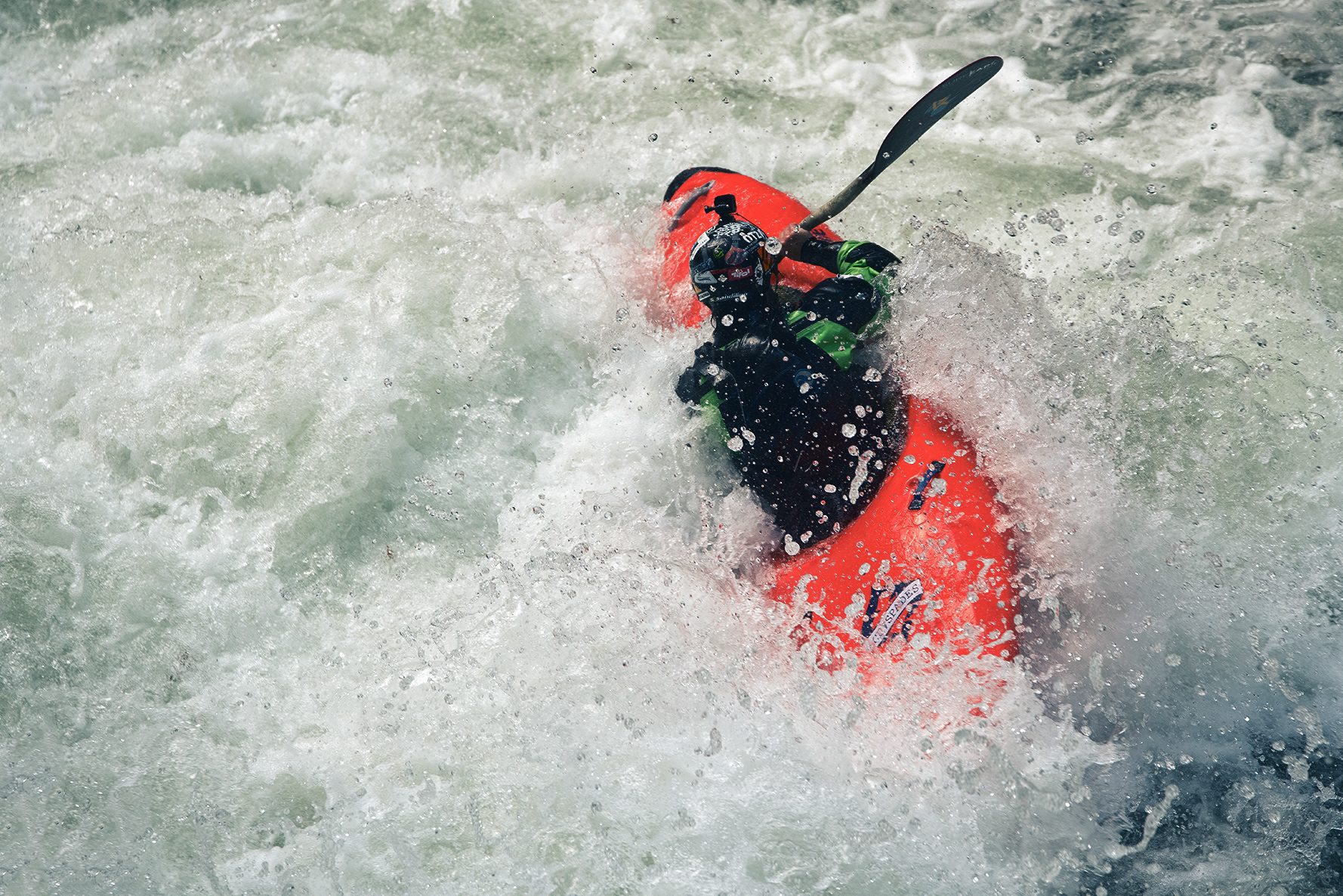 Kayak rosso dentro la schiuma di una rapida