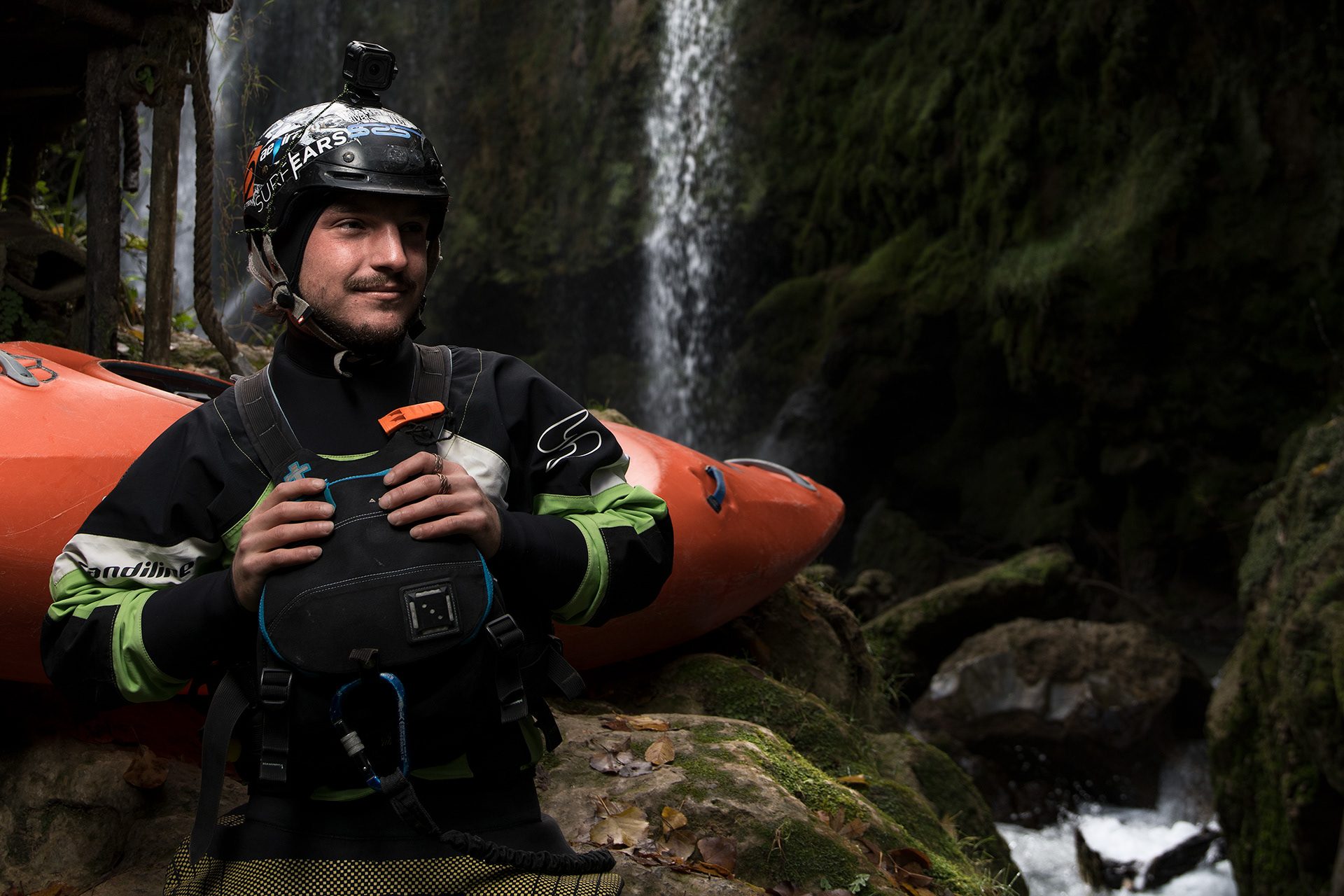 Kayaker seduto accanto alla canoa davanti a una cascata