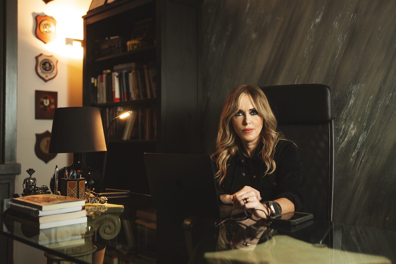 Donna seduta alla scrivania in uno studio arredato, ritratto ambientato
