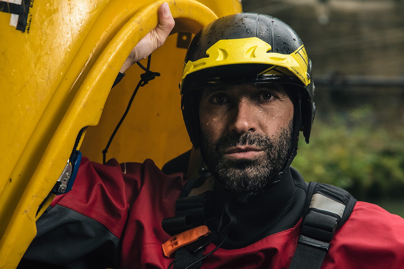 Kayaker con il casco giallo sotto lo scafo della canoa