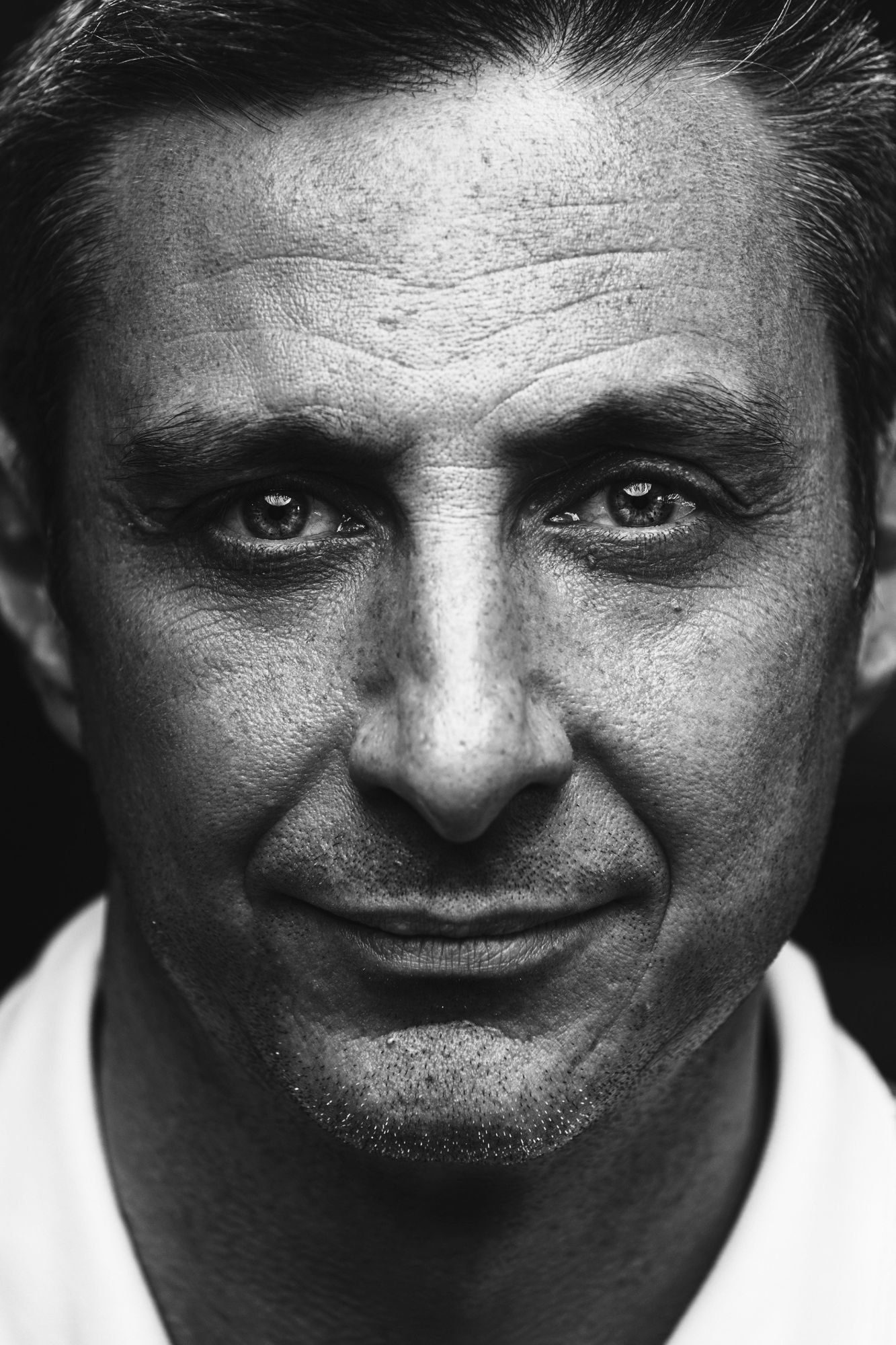 Ritratto in bianco e nero di un uomo sorridente, primissimo piano