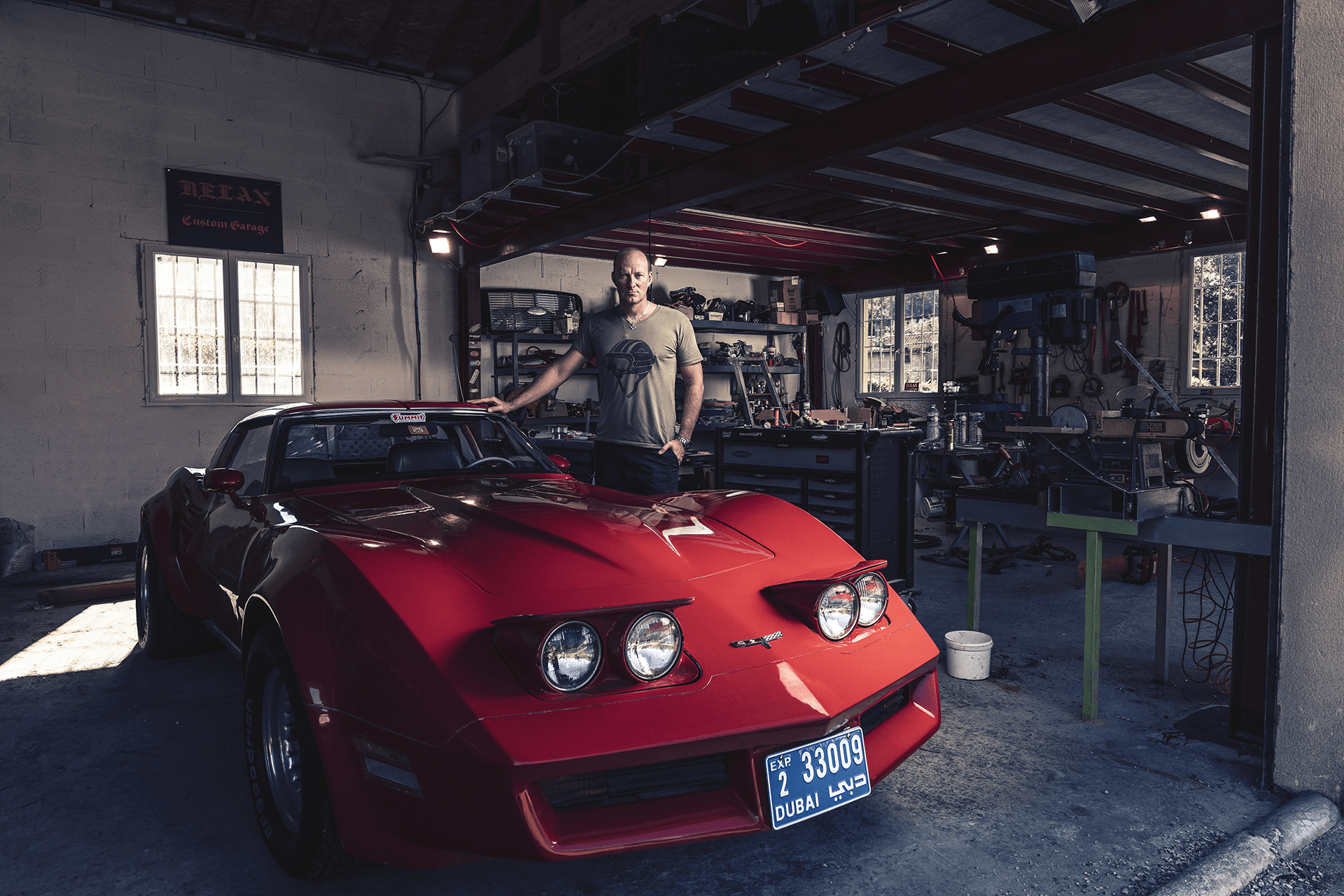 Uomo accanto a una Corvette rossa nella sua officina